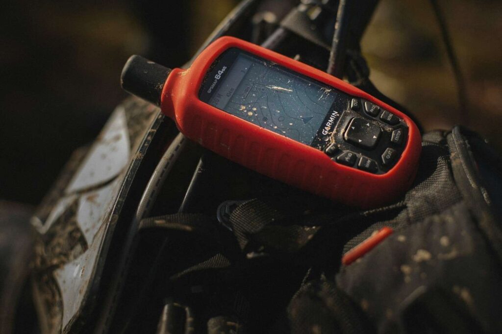Handheld Garmin GPS tracking device used for outdoor navigation, illustrating a Garmin Alpha dog tracker system.
